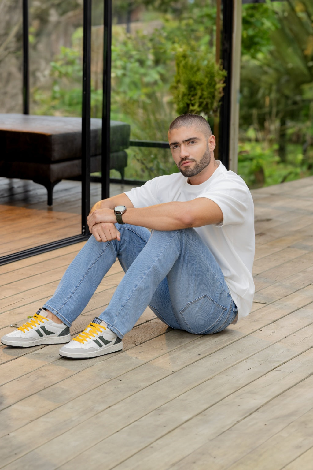 Tenis Casual Napa con Apliques en Nobuck y Cordones Dobles - modelo sentado en terraza de madera usando tenis blanco casual