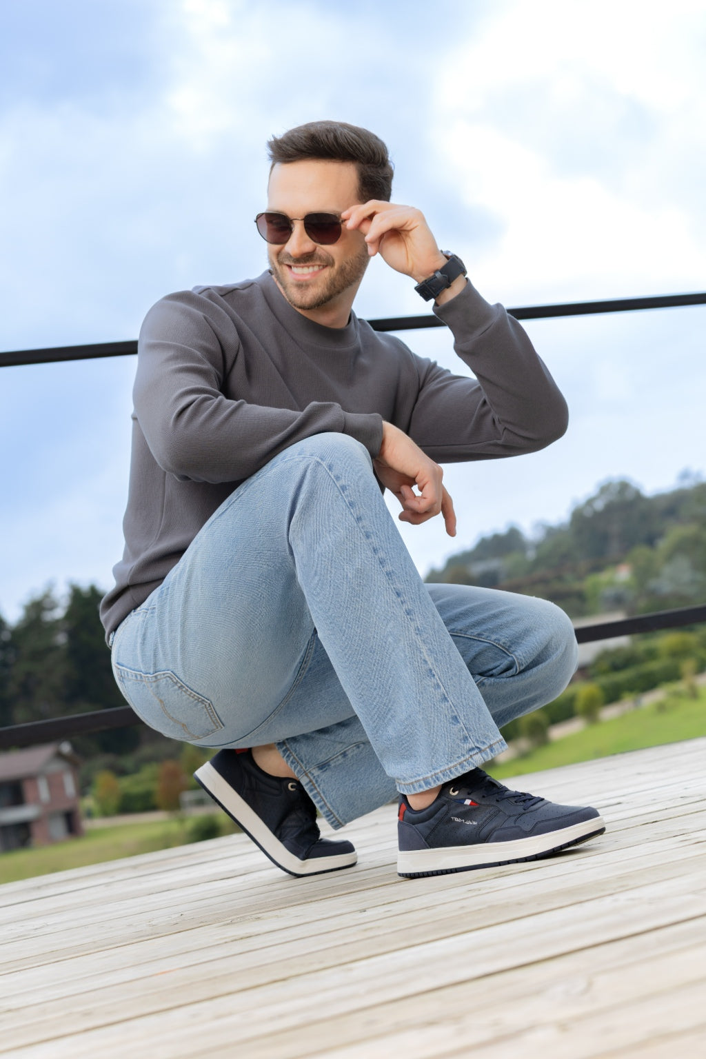 Tenis Deportivo Napa con Apliques en Nobuck - modelo sentado en terraza de madera usando tenis azul