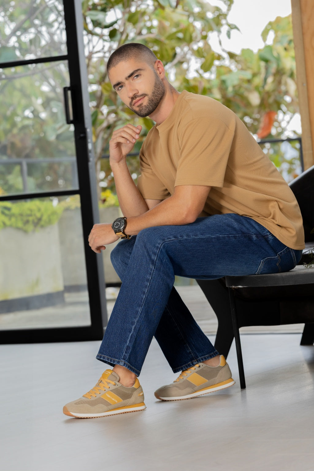Tenis Deportivo en Lona con Apliques en Nobuck y Napa Beige - modelo sentado en terraza usando tenis beige casual